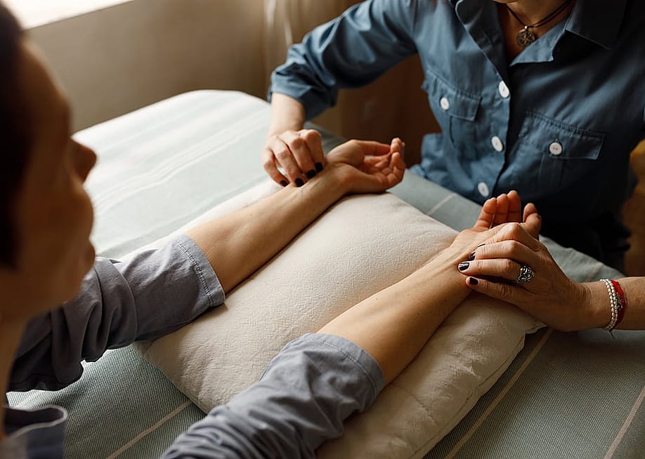 A female acupuncturist performing physical examinations on a patient's hands. — shurkin_son // Shutterstock