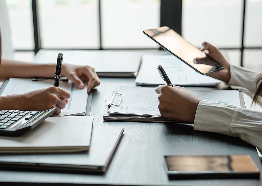 Accountants checking physical reports to finalize project figures. — mojo cp // Shutterstock