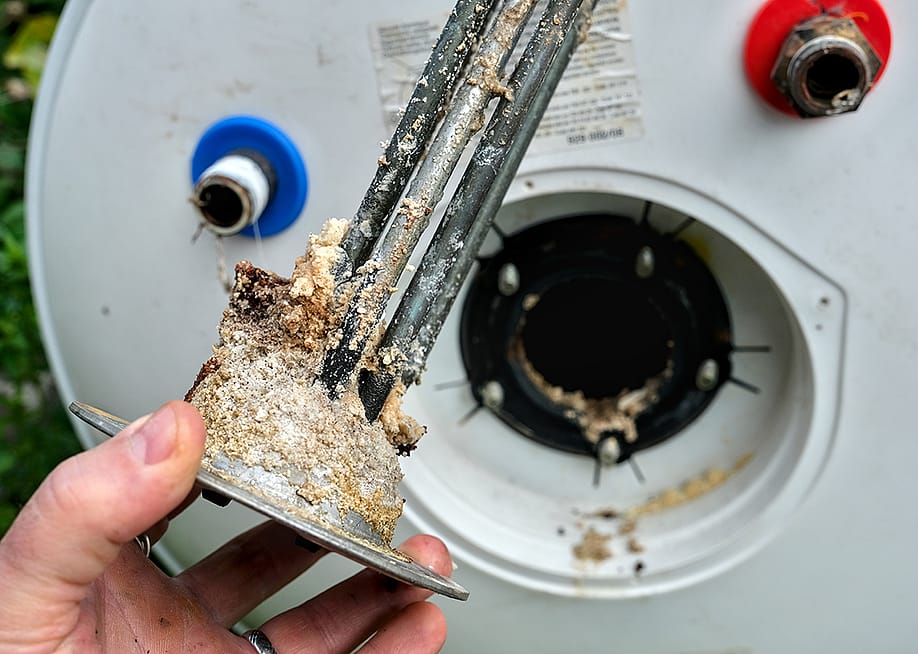 An electric water heater heating element covered in a thick crust of limescale and hard water minerals. — Igor Paszkiewicz // Shutterstock