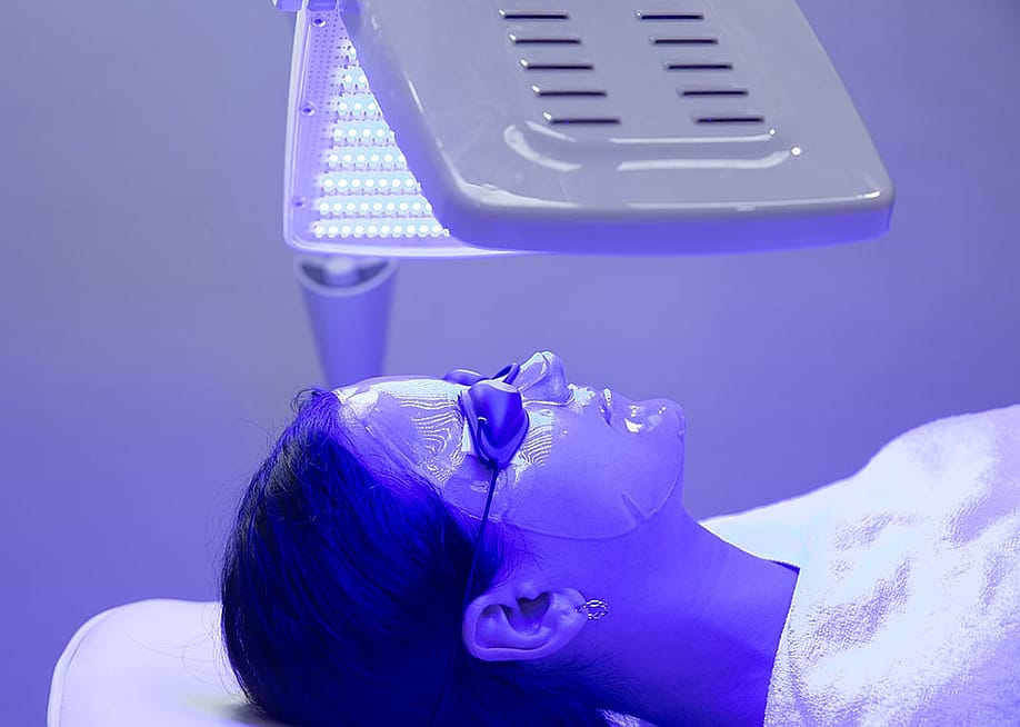A young woman having blue LED light facial therapy. — Space_Cat // Shutterstock