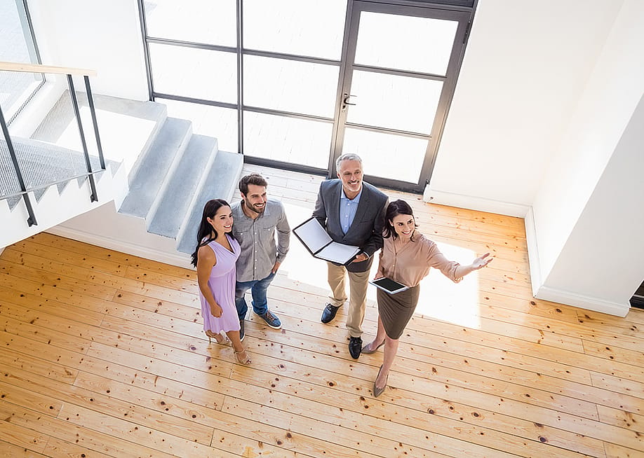 Real estate agents show a young couple the interior of a new house. — wavebreakmedia // Shutterstock