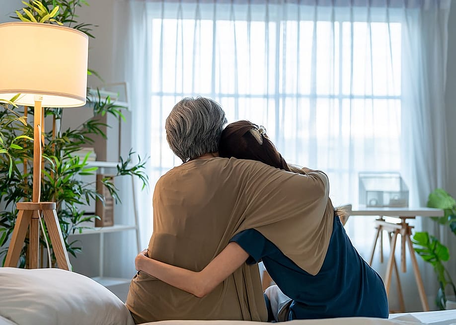 Rear view of an elderly mother comforting her daughter at home. — Hananeko_Studio // Shutterstock
