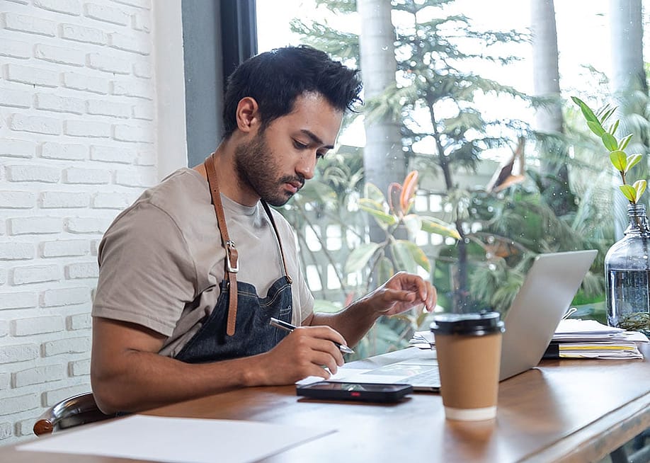 A cafe owner reviewing business documents. — Simplylove // Shutterstock