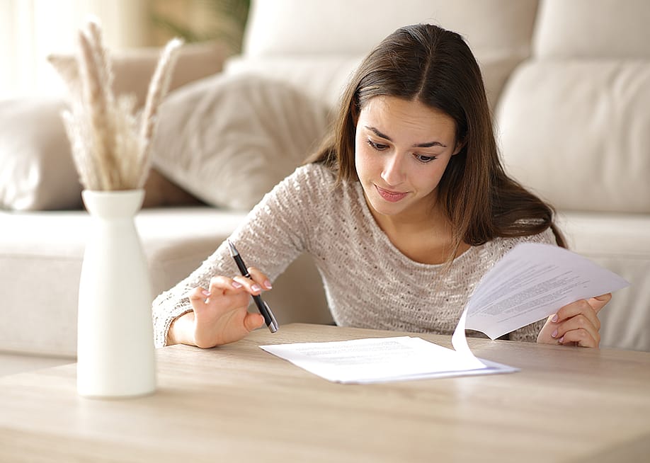 A person reviewing the coverage and cash value of her life insurance policy at home. — Antonio Guillem // Shutterstock