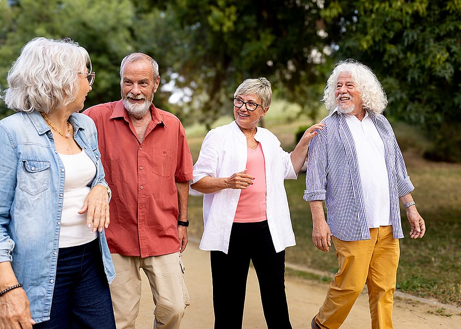 A group of elderly people enjoying a slow walk over happy conversations outdoors at the park. — Daniel Hoz // Shutterstock