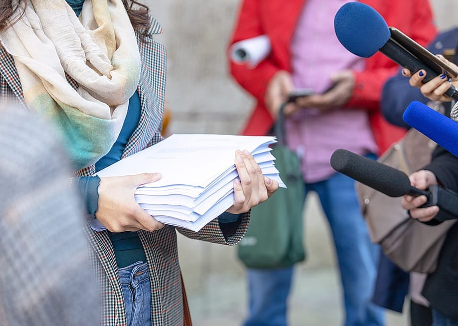 A whistleblower holding relevant documents and speaking to press for a media interview. — wellphoto // Shutterstock