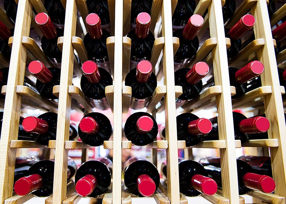 A group of red wine bottles stacked on wooden racks. — hxdbzxy // Shutterstock