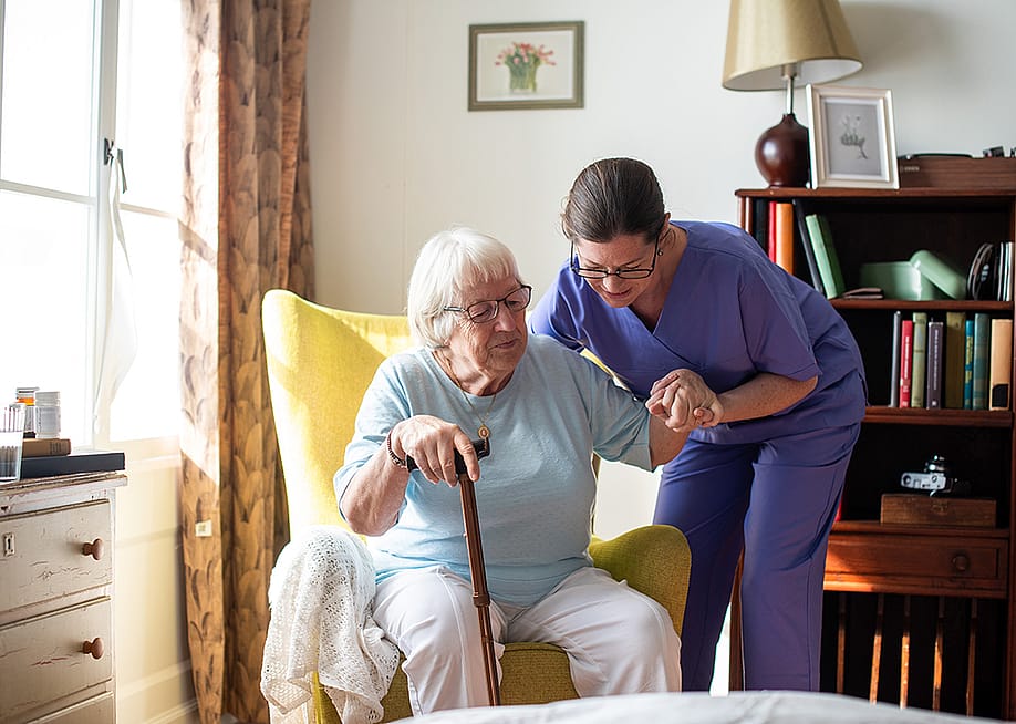 A caregiver assisting an elderly patient to stand up slowly in the morning. — Rawpixel.com // Shutterstock