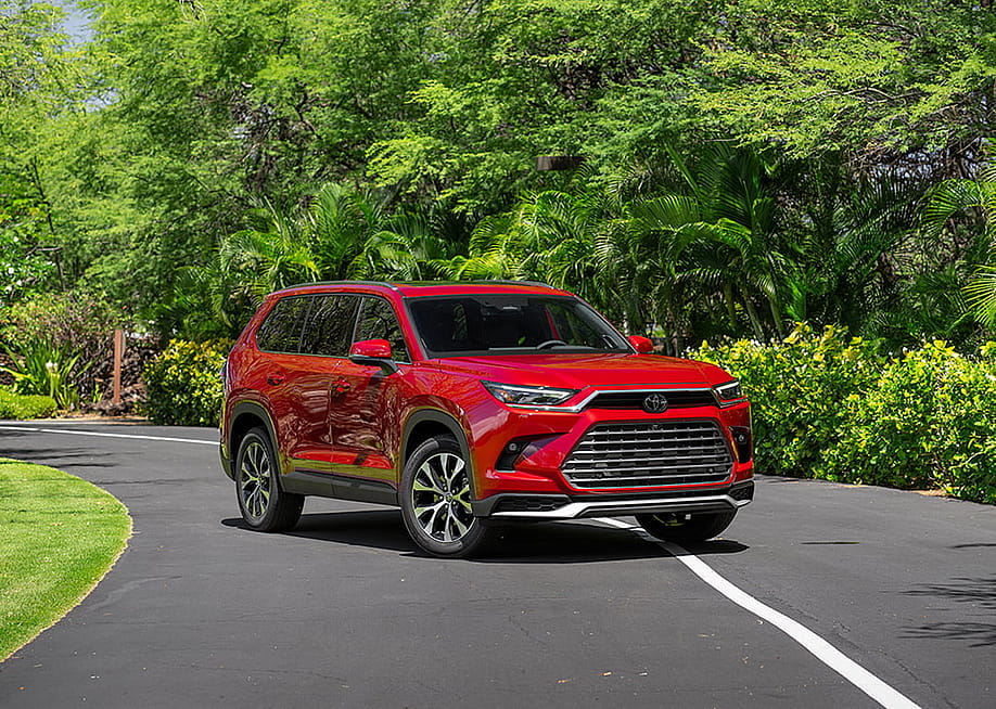 A 2026 Toyota Grand Highlander Platinum in Ruby Flare Pearl parked in an asphalt driveway. — Toyota