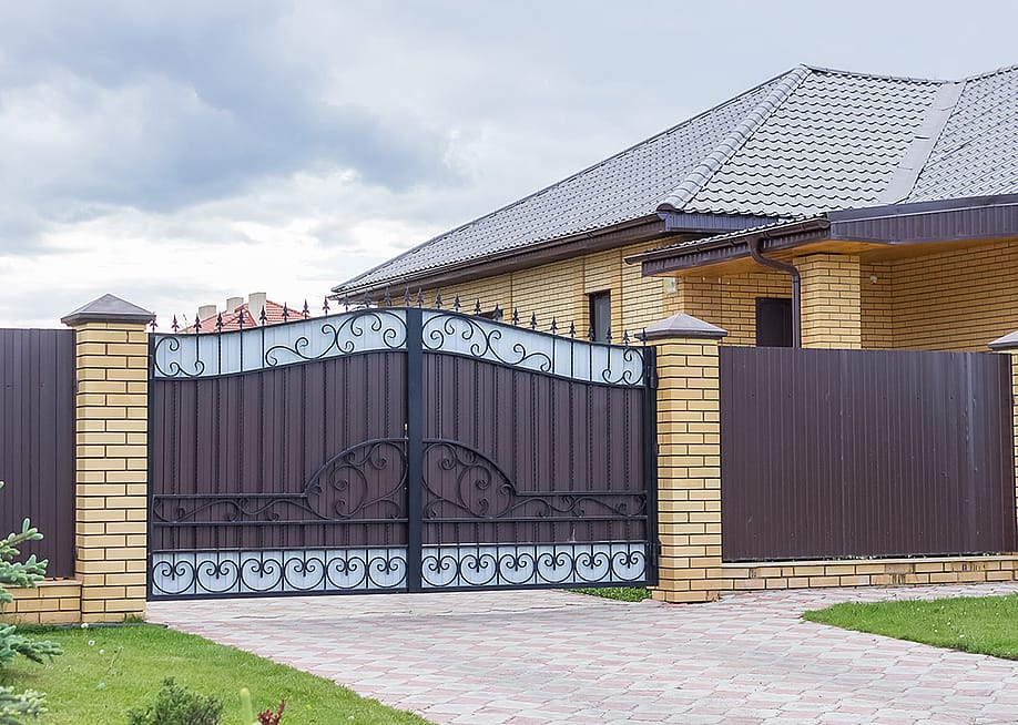 Brown automatic gates at the entrance of a modern house and lot. — Magnetolga // Shutterstock