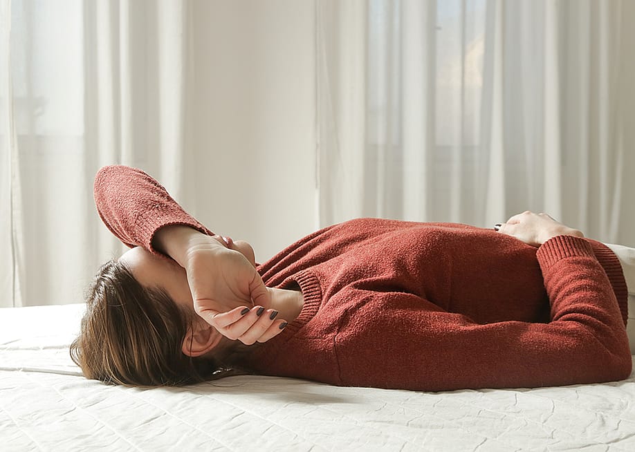 A tired woman laying in bed. — triocean // Shutterstock