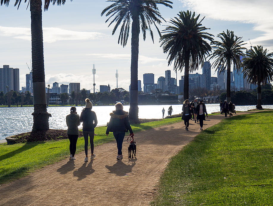 Groups of people in face masks exercise, running and walking around Albert Park Lake during COVID-19 lockdown. — Christie Cooper // Shutterstock