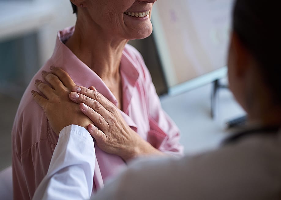 A doctor touching an elderly patient's shoulder as a comforting gesture before her hospital treatment. — Dragon Images // Shutterstock