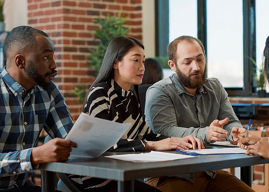 A group of employees engaged in a tense conversation at work. — DC Studio // Shutterstock