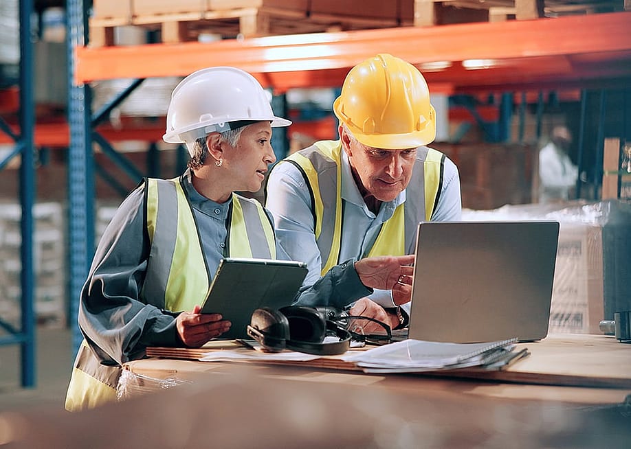 Inventory managers checking schedules for the shipment of large packages in a warehouse. — PeopleImages // Shutterstock
