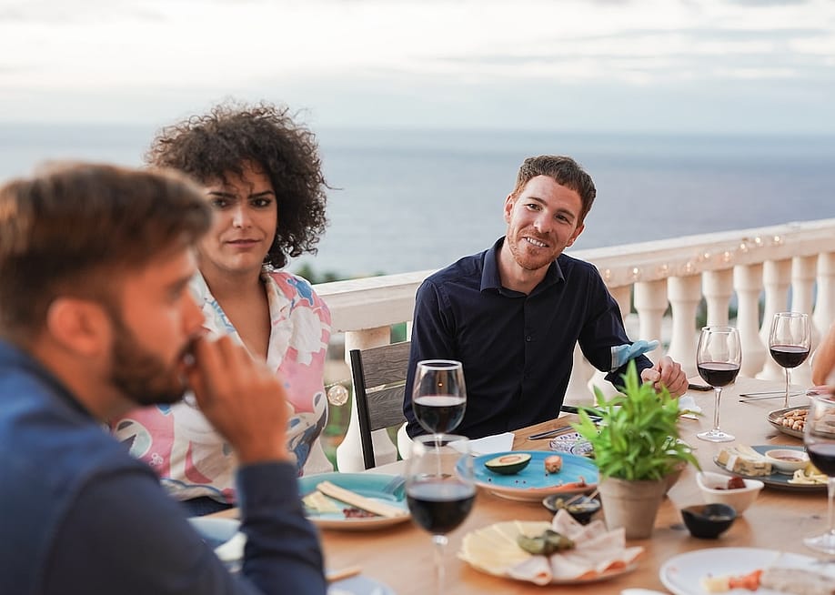 Group of diverse young friends enjoying dinner at a home patio. — Sabrina Bracher // Shutterstock