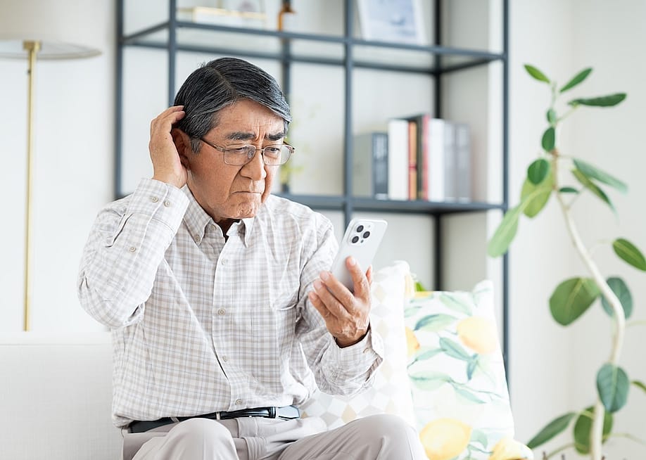 A confused senior man looking at his phone. — pain au chocolat // Shutterstock