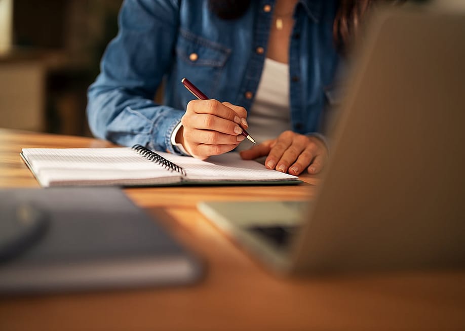 A university student working on class notes and requirements in the library. — Jelena Zelen // Shutterstock
