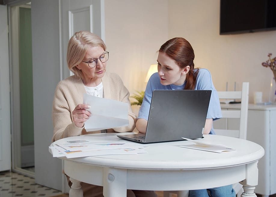 A senior mother reviewing documents together with her adult daughter. — iaginzburgh // Shutterstock