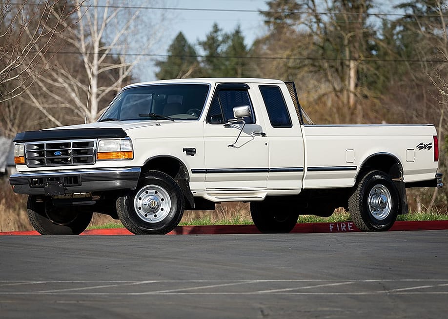 A white 1997 Ford F-250 XLT heavy-duty pickup truck parked outdoors. — Hrach Hovhannisyan // Shutterstock