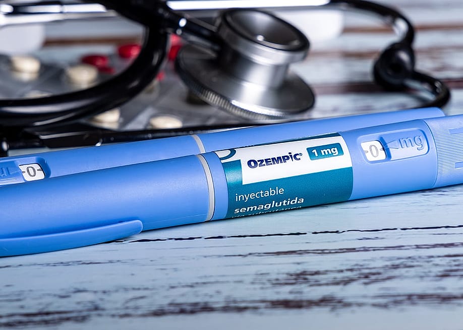 Ozempic semaglutide GLP-1 injection pens seem next to medicine pills and a stethoscope. — Edugrafo // Shutterstock