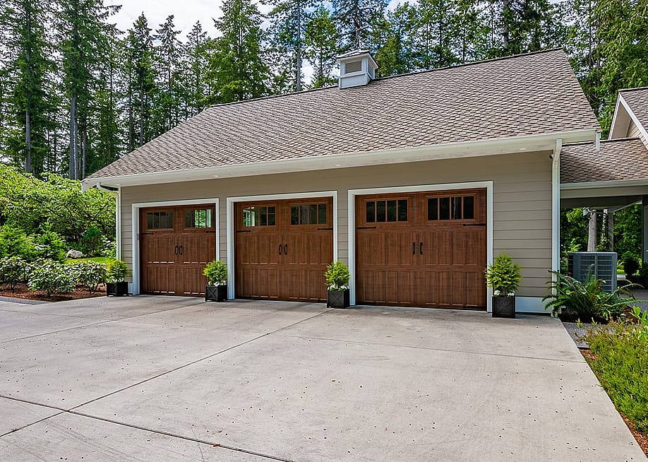 A craftsman style home with a three-car garage with lush and spring foliage landscape outside. — Sheila Say // Shutterstock