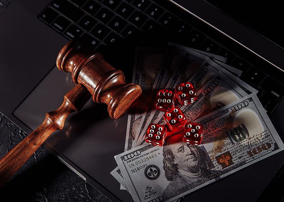 A gavel, dice, and U.S. dollar bills placed on top of a laptop, representing the concept of online gambling. — Burdun Iliya // Shutterstock