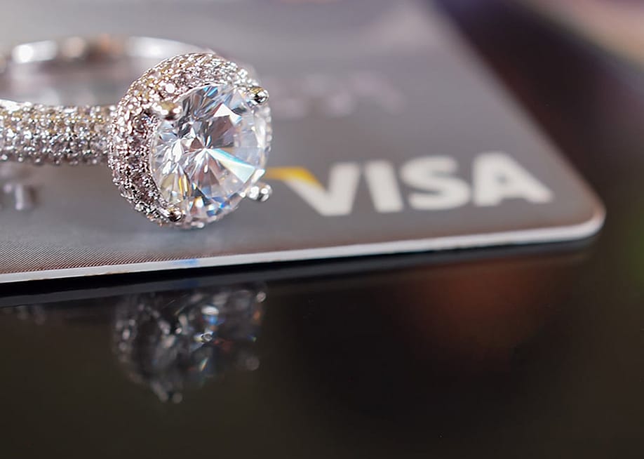 A diamond engagement ring placed above a credit card. — DUANGJAN J // Shutterstock