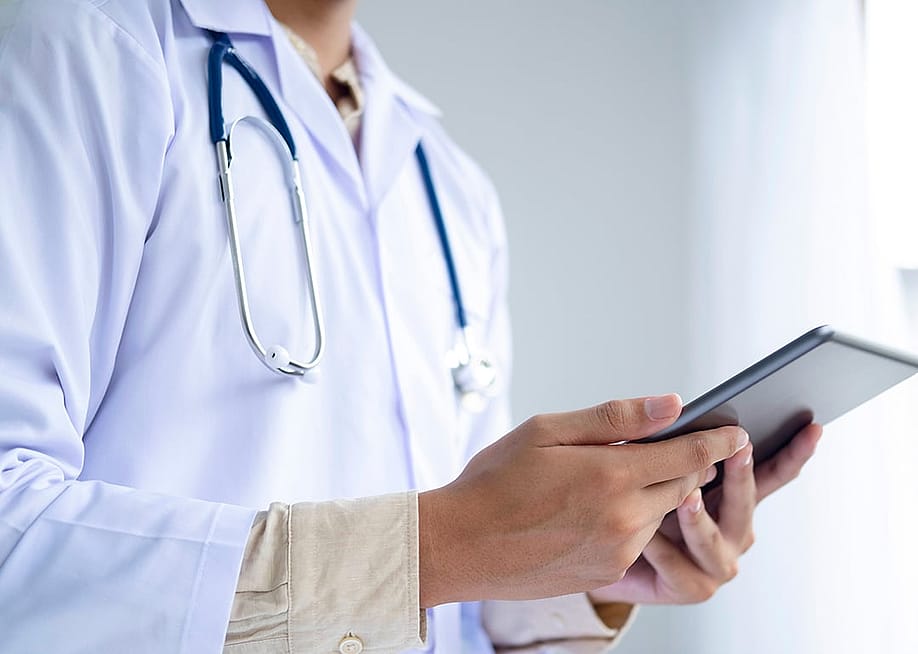 A medical doctor holding a digital tablet with patients' charts in a clinic. — iJeab // Shutterstock