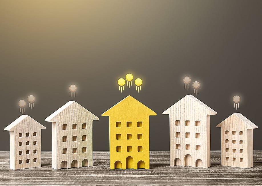 Miniature building models with glowing coins rising from their roofs, representing rising prices in the real estate market. — Andrii Yalanskyi // Shutterstock
