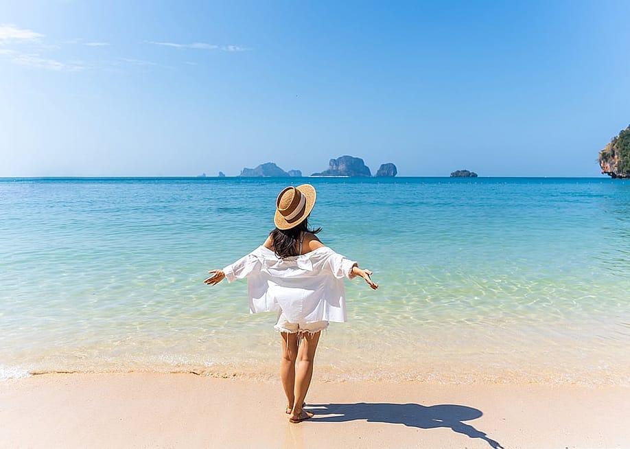 A person enjoying the beautiful white sand beach on a sunny day during a vacation. — kitzcorner // Shutterstock
