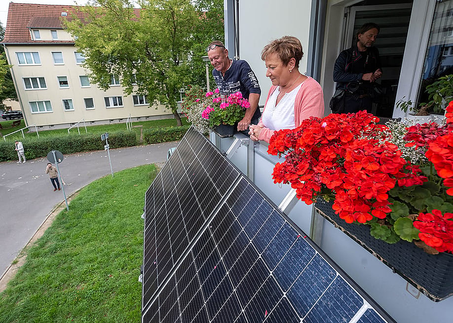 Tenants Kathrin Kother and Swen Bruske looking over their new balcony power plant with flower pots at their apartment in Taucha, Saxony, Germany. — Hendrik Schmidt // picture alliance via Getty Images