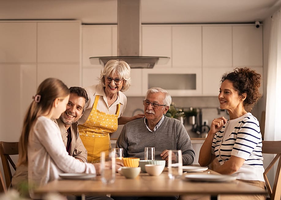A multigenerational family sharing stories over a reunion dinner in the dining table. — Jelena Zelen // Shutterstock