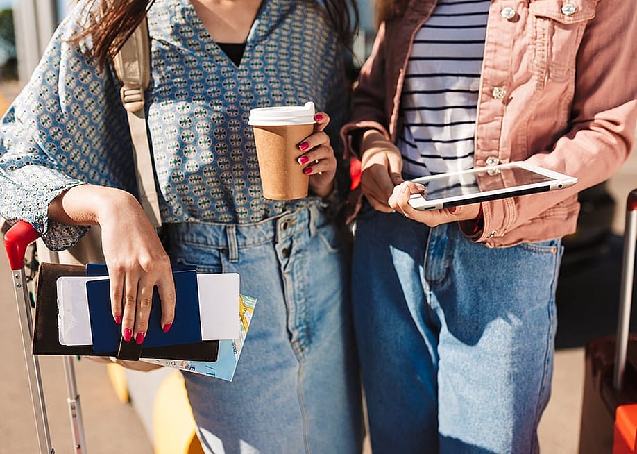 Young adults holding their travel essentials and suitcases while walking to the outdoor tarmac of their plane. — garetsworkshop // Shutterstock