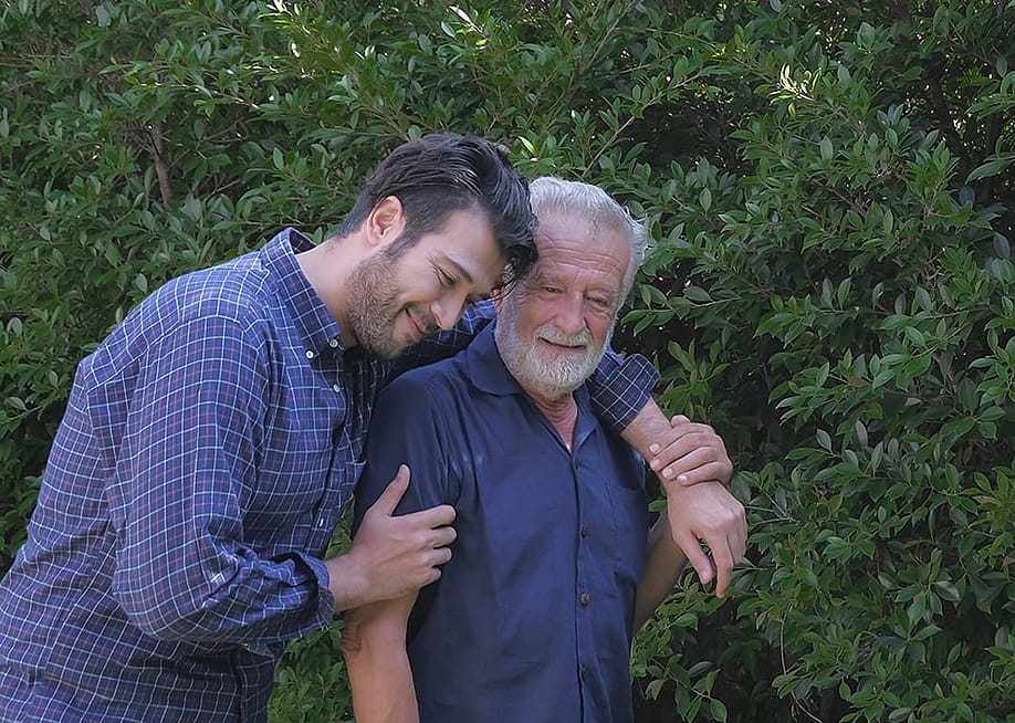 An adult son and his elderly father bonding during a slow walk in the garden. — Parinya.Maneenate // Shutterstock