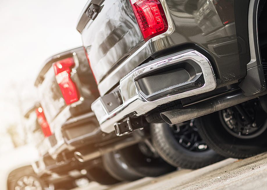 A line of brand new pickup trucks for sale parked outside a car dealership. — Virrage Images // Shuttertock