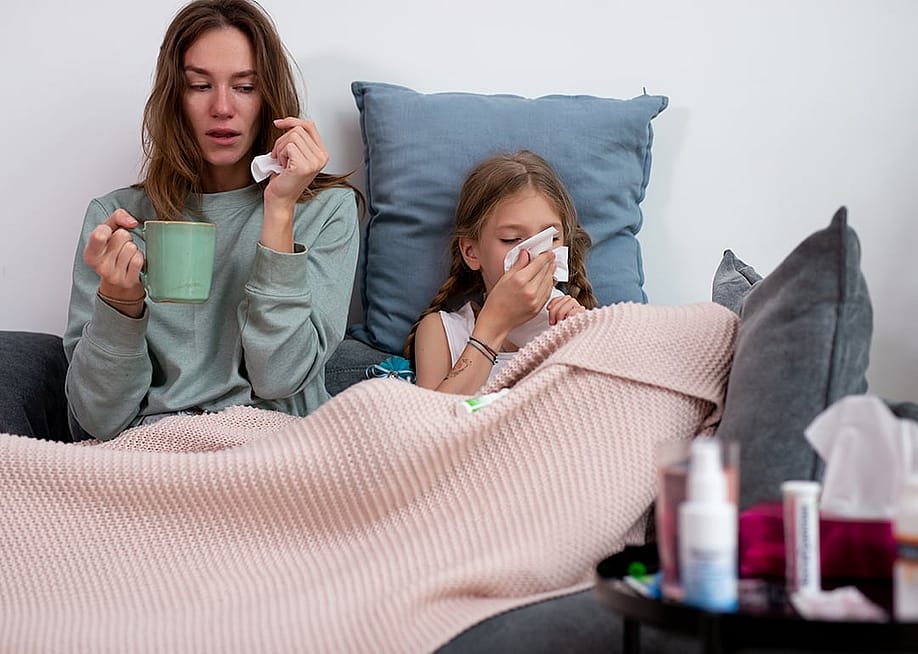 A mother and child feeling sick together in a couch at their bedroom. — Undrey // Shutterstock