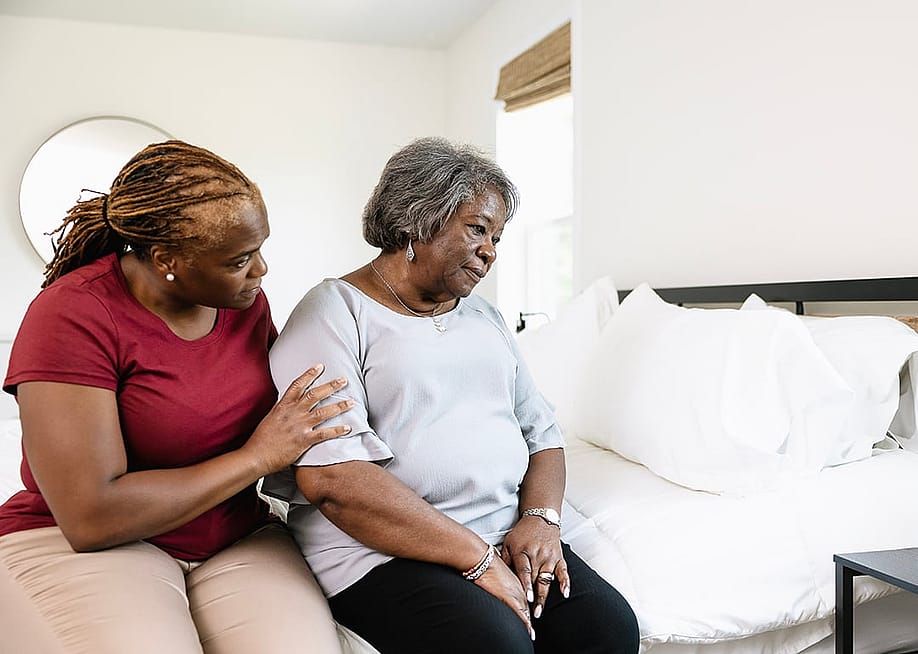 A home caregiver comforting a worried elderly patient in the bedroom. — Aeroflow Urology