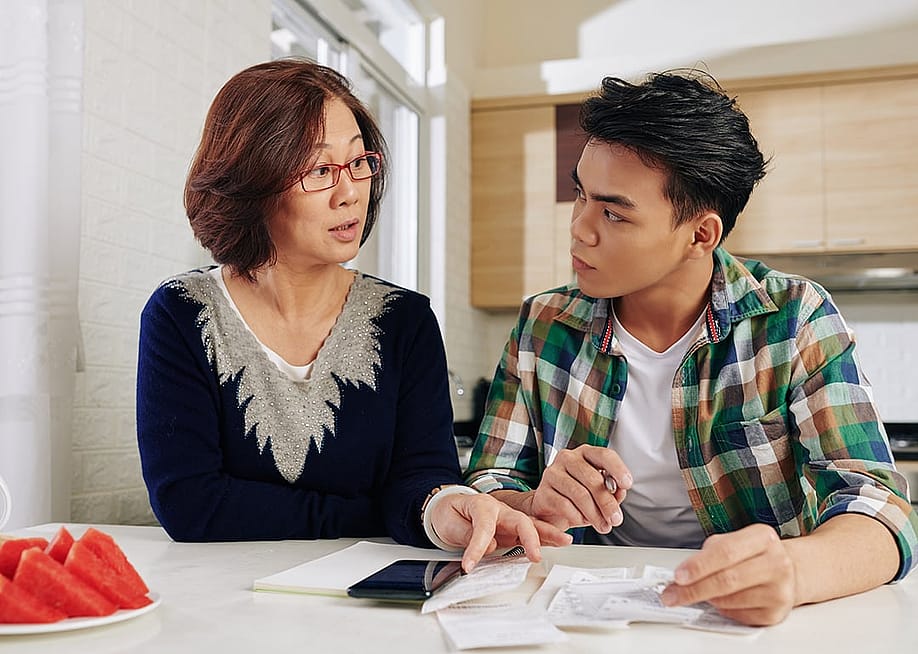 A mother advising her young son on school and expenses. — Dragon Images // Shutterstock