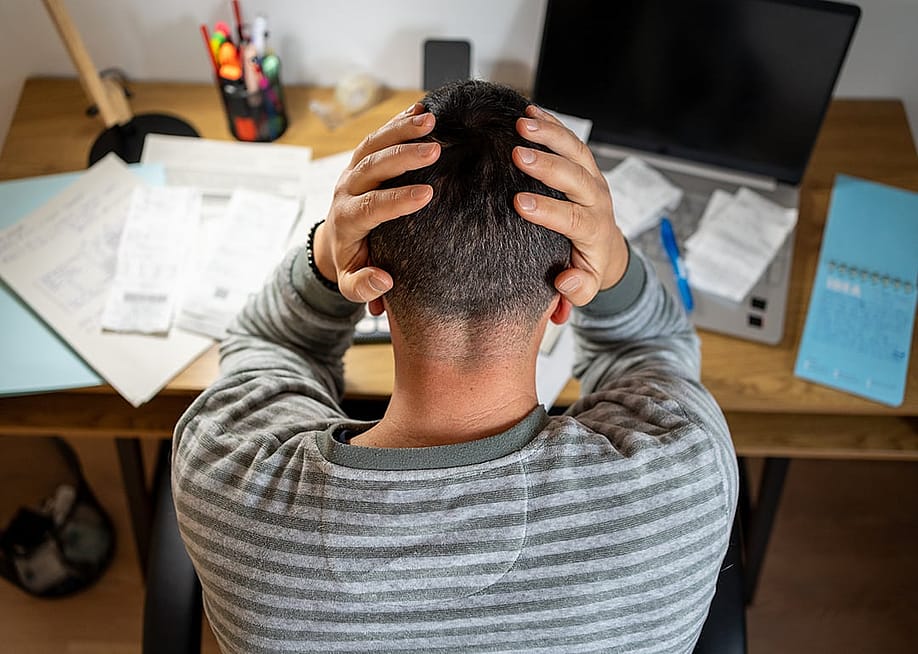 A business owner gesturing frustration while reviewing finance documents. — Jota Buyinch Photo // Shutterstock