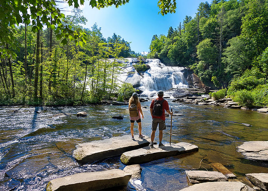 A couple standing on a rock enjoying beautiful waterfall view. — Margaret.Wiktor // Shutterstock