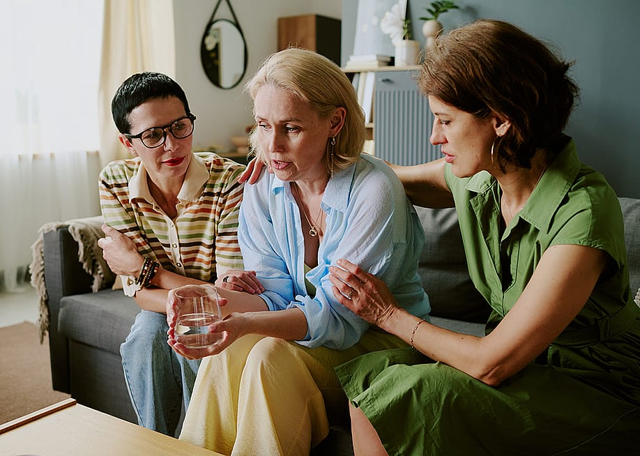 A group of middle-aged female friends comforting each other. — AnnaStills // Shutterstock