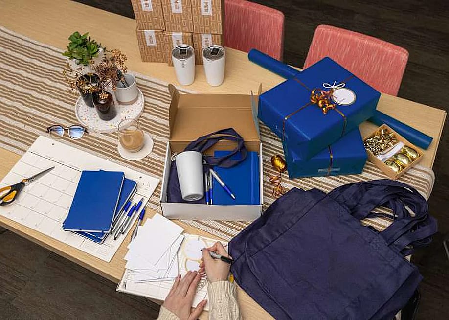 An HR person packing corporate holiday gifts and branded merchandise of their company. — Custom Ink