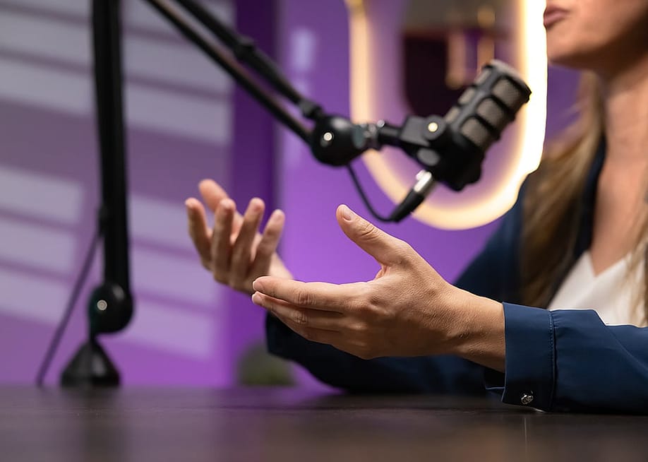 Closeup of female host talking into professional microphone during live discussion. — fizkes // Shutterstock