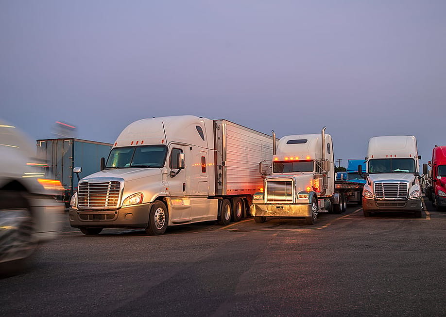 A row of big semi trucks on the road. — Vitpho // Shutterstock