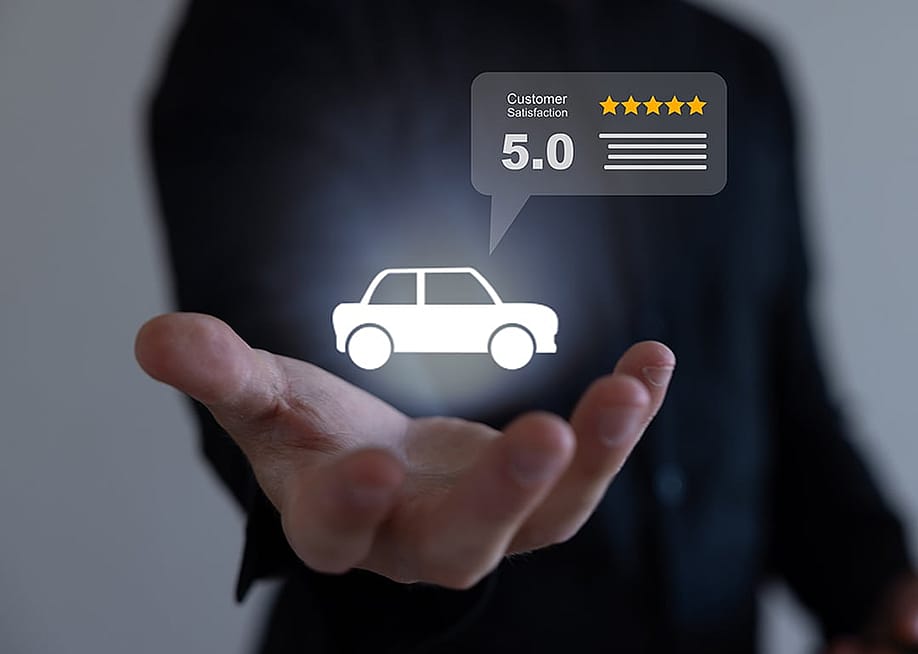 A conceptual photo featuring a business owner holding a glowing car icon with its high customer satisfaction rating for their auto repair shop's review. — Runawayphill // Shutterstock
