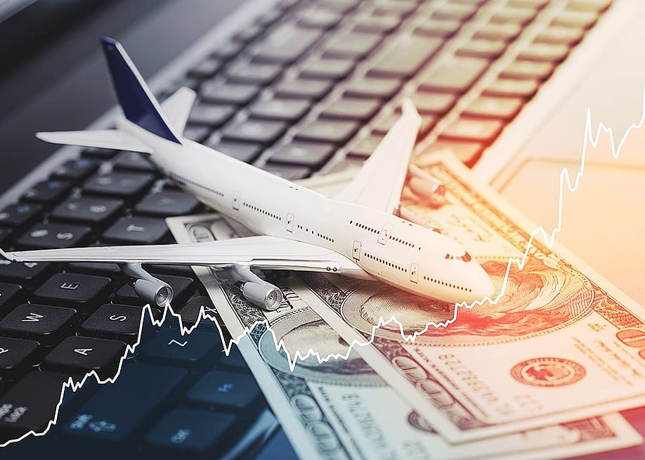 A conceptual photo showing a computer, an aircraft toy, and U.S. dollar bills and overlaying a rising stock chart, representing increased airfare rates. — BLACKDAY // Shutterstock