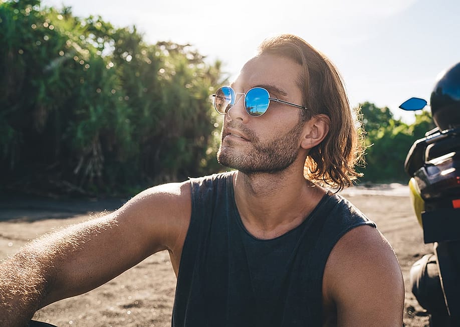 A person with sunglasses enjoying the summer sunny weather outdoors. — GaudiLab // Shutterstock