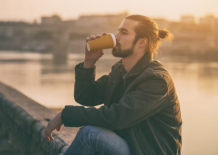 A man drinking coffee outdoors. — InesBazdar // Shutterstock