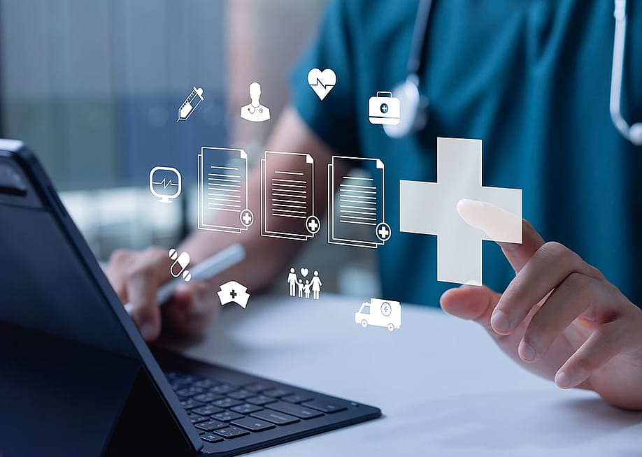 A healthcare professional using a laptop and tablet with floating holographic icons representing electronic medical records. — Father - Studio // Shutterstock